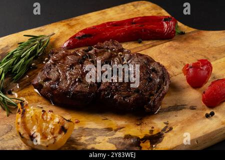 Leckerer Rib Eye Black Angus serviert mit Pfeffer und Kräutern auf Holzbrett. Stockfoto