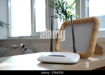 Moderner wlan-Router mit Rahmen auf Regal im Zimmer, Nahaufnahme Stockfoto