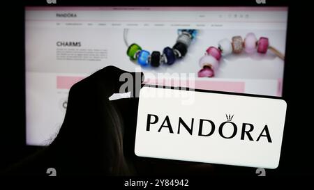 In dieser Abbildung hält eine Person ein Smartphone mit dem Logo des dänischen Schmuckunternehmens Pandora vor der Website. Stockfoto