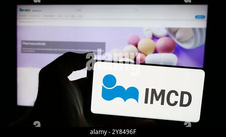 In dieser Abbildung hält eine Person ein Smartphone mit dem Logo des niederländischen Spezialchemieunternehmens IMCD N.V. vor der Website. Stockfoto