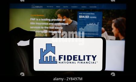 In dieser Abbildung befindet sich ein Mobiltelefon mit dem Logo des US-Finanzunternehmens Fidelity National Financial Inc. Vor der Webseite des Unternehmens. Stockfoto