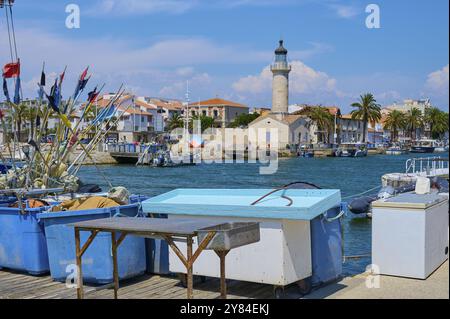 Küstenstadt mit bunten Häusern und Palmen, Booten im Wasser und Leuchtturm, an einem sonnigen Tag, im Sommer, Le Grau-du-ROI, Gard, Mittelmeer SE Stockfoto