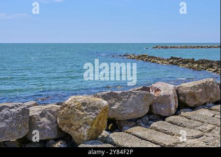 Felsige Küste mit klarem blauem Mittelmeer und sonnigem Himmel, Saintes-Maries-de-la-Mer, Camargue, Frankreich, Europa Stockfoto