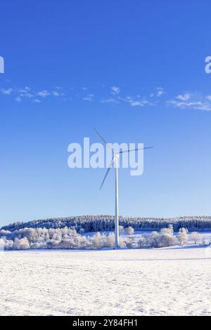 Windkraftanlage auf einem Feld in einer ländlichen Landschaft mit Schnee und Frost an einem kalten, sonnigen Wintertag. Schweden Stockfoto