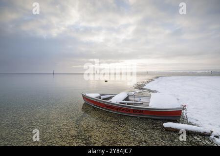 Ein Rettungsboot liegt am schneebedeckten Seeufer unter bewölktem Himmel, Strandbad Hoernle, Konstanz, Bodensee, Baden-Württemberg, Deutschland, Europa Stockfoto