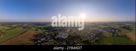 Sonnenaufgang weites Luftpanorama der niederländischen Stadt Voorst in der flachen Landlandschaft der Niederlande, während die Sonne am Horizont bunte Schatten wirft Stockfoto