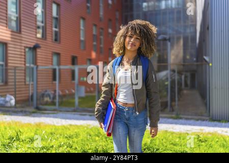 Beauty latin Student steht vor der Universität und lächelt in die Kamera und trägt Mappen, Notizbücher und Rucksack Stockfoto