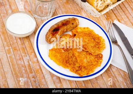 Kartoffelpfannkuchen mit Wurst und Sauerrahm Stockfoto