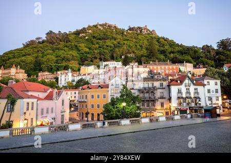 Maurisches Schloss Sintra Portugal // SINTRA, Portugal – das alte maurische Schloss (Castelo dos Mouros) steht auf einem Hügel mit Blick auf die historische Stadt Sintra. Die Festung wurde im 8. Und 9. Jahrhundert von den Mauren erbaut, die die iberische Halbinsel besetzten. Sie besteht aus Steinmauern, die sich entlang des bergigen Geländes schlängeln. Die zum UNESCO-Weltkulturerbe gehörende Stadt Sintra breitet sich im Vordergrund mit ihrer unverwechselbaren Architektur und den roten Ziegeldächern aus. Sintra liegt etwa 25 Kilometer westlich von Lissabon und ist bekannt für seine romantischen Paläste aus dem 19. Jahrhundert und üppige Vegetation. Th Stockfoto