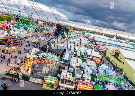 Flug durch den Münchner Himmel, vom Kettenflieger Bayern Tower bietet sich ein toller Blick auf das Oktoberfest, München, Oktober 2024 Deutschland, München, Oktober 2024, Wiesnbesucher genießen den Flug durch den Münchner Himmel, in 90 Meter Höhe haben sie einen wunderbaren Blick über das Oktoberfest, Kettenflieger Bayern Tower, 90 Meter hohes Kettenkarussell, Theresienwiese, Fahrgeschäft gehört Schausteller Egon Kaiser, Mittwochabend, Himmel bewölkt, Wiesnwetter, bayerisch, Volksfest, Herbst, Bayern, *** Flug durch den Münchner Himmel, vom Kettenflieger Bayern Turm hat man eine tolle Aussicht Stockfoto