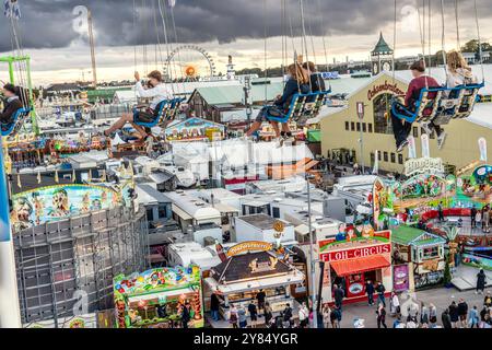 Flug durch den Münchner Himmel, vom Kettenflieger Bayern Tower bietet sich ein toller Blick auf das Oktoberfest, München, Oktober 2024 Deutschland, München, Oktober 2024, Wiesnbesucher genießen den Flug durch den Münchner Himmel, in bis zu 90 Meter Höhe haben sie einen wunderbaren Blick über das Oktoberfest, hier zum Ende der Fahrt sind sie noch in 25 Meter Höhe, Kettenflieger Bayern Tower, 90 Meter hohes Kettenkarussell, Theresienwiese, Fahrgeschäft gehört Schausteller Egon Kaiser, Mittwochabend, Himmel bewölkt, Wiesnwetter, bayerisch, Volksfest, Herbst, Bayern, *** Flug durch den Munic Stockfoto