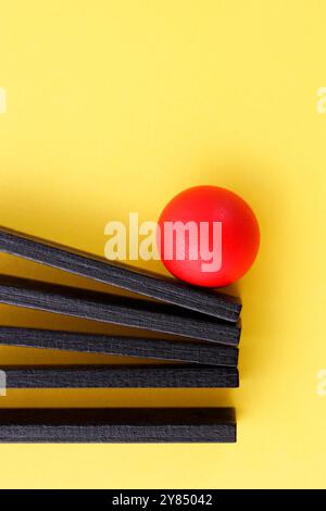 Kugel, die mehrere Holzfiguren in einer Reihe schiebt Stockfoto