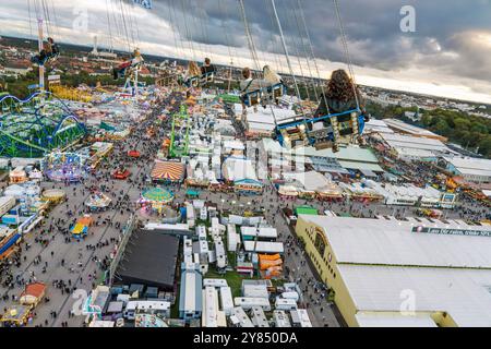 Flug durch den Münchner Himmel, vom Kettenflieger Bayern Tower bietet sich ein toller Blick auf das Oktoberfest, München, Oktober 2024 Deutschland, München, Oktober 2024, Wiesnbesucher genießen den Flug durch den Münchner Himmel, in 90 Meter Höhe haben sie einen wunderbaren Blick über das Oktoberfest, Kettenflieger Bayern Tower, 90 Meter hohes Kettenkarussell, Theresienwiese, Fahrgeschäft gehört Schausteller Egon Kaiser, Mittwochabend, Himmel bewölkt, Wiesnwetter, bayerisch, Volksfest, Herbst, Bayern, *** Flug durch den Münchner Himmel, vom Kettenflieger Bayern Turm hat man eine tolle Aussicht Stockfoto