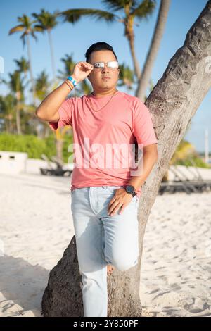 Modellierung von Herrenmode und bequemer Kleidung junger lateinmann mit Sonnenbrille, jeans und T-Shirt, entspannter Lifestyle, Strandlandschaft Stockfoto