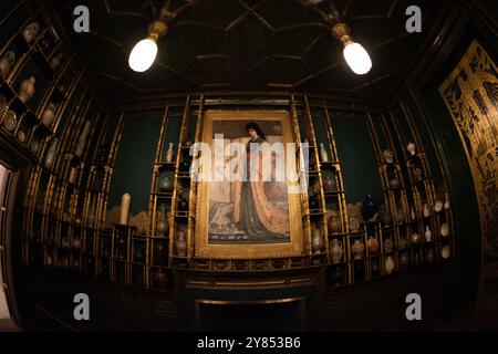 Freer Gallery Peacock Room Washington D.C. // WASHINGTON, D.C. — Rose und Silber: Die Prinzessin aus dem Land des Porzellans von James McNeill Whistler zeigt Christina Spartali, ein anglo-griechisches Modell aus einer prominenten Familie, das in einem Kimono zwischen asiatischen Keramiken und Objekten posiert. Das Gemälde, das als zentraler Mittelpunkt des Pfauensaals dient, fängt die Mode des Japonismus aus dem 19. Jahrhundert durch Spartalias kontemplative Pose und Fächer ein. Obwohl Whistler das Werk nicht als wörtliches Porträt vorhatte, spiegelt die Komposition seine Auseinandersetzung mit imaginären östlichen Themen wider, die während der Aesthet populär waren Stockfoto