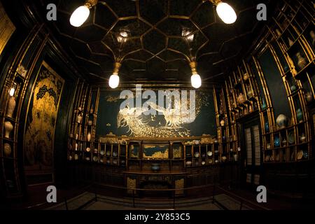 Peacock Room Mural National Museum of Asian Art Washington DC // WASHINGTON, D.C. — Ein Wandbild mit zwei kämpfenden Pfauen ziert die Südwand von James McNeill Whistlers berühmtem Peacock Room im National Museum of Asian Art Dieses Wandgemälde mit dem Titel „Art and Money; Or, The Story of the Room“ wurde 1876–1877 geschaffen und stellt Whistlers künstlerische Vergeltung gegen seinen Mäzen Frederick Richards Leyland nach deren bitterem Finanzstreit dar. Der Pfau auf der rechten Seite, der Leyland repräsentiert, weist silberne Kehlfedern auf, die auf das markante weiße Rüschenhemd des Schiffsmagnaten verweisen Stockfoto