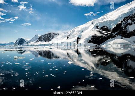 NEKO HARBOUR, Antarktis – die zerklüfteten Berge und Gletscher rund um den Neko Harbour sorgen für perfekte Reflexionen in den ungewöhnlich ruhigen antarktischen Gewässern. Die unberührte Polarlandschaft mit eisbedeckten Gipfeln und Felsvorsprüngen spiegelt sich mit außergewöhnlicher Klarheit in der glasklaren Oberfläche des Hafens wider. Dieser abgelegene Ort auf der Antarktischen Halbinsel zeigt das dramatische Gletschergebiet der Region. Stockfoto