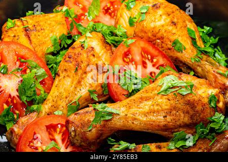 Saftig gebackene Hähnchenschenkel mit Tomaten und Gemüse. Stockfoto