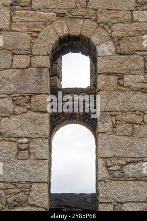 Römischer Bogen in der Mauer des alten kornischen Zinnbergwerks aus kornischem Granit, Botallack nahe Land’s End, Cornwall, England, Großbritannien. Stockfoto