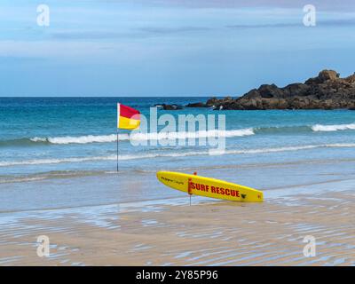 Gelbes Surfbrett und gelbe und rote Rettungsfahne am Porthmeor Beach, St. Ives, Cornwall, England, Großbritannien Stockfoto