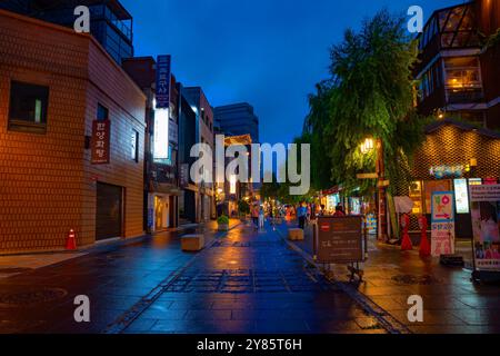 Friedliche Abendstraße in Insadong, Seoul, kurz nach dem Regen. Der nasse Bürgersteig reflektiert die Lichter der Geschäfte und schafft so ein ruhiges Ambiente. Stockfoto