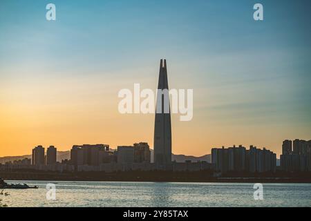 Dieses Foto zeigt den Blick auf den Sonnenaufgang, wobei die Skyline der Stadt allmählich vom Morgenlicht beleuchtet wird und das höchste Gebäude deutlich hervorhebt. Stockfoto