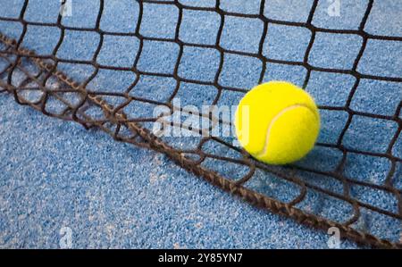 Ball im Schatten des Netzes eines blauen Paddle-Tennisplatzes. Stockfoto