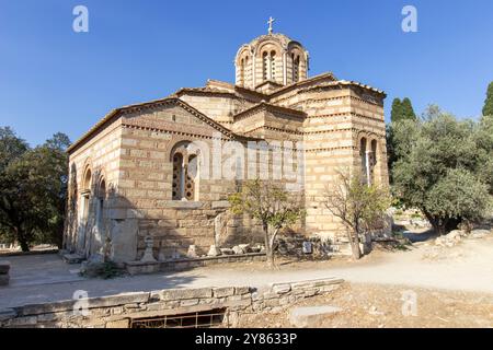 Alte Steinkirche im byzantinischen Stil mit Kuppeldach und Kreuz auf der Spitze, umgeben von Bäumen und Pfad in Athen, Griechenland. Architektonische Fotos im Freien Stockfoto