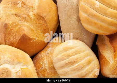 Frisch gebackene Brotlaibe, die in einem Korb gekühlt werden und verschiedene Texturen und Krusten zeigen Stockfoto