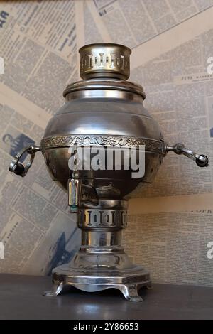 Russischer Retro-Samovar vor dem Hintergrund von Zeitungen aus der Sowjetzeit Stockfoto