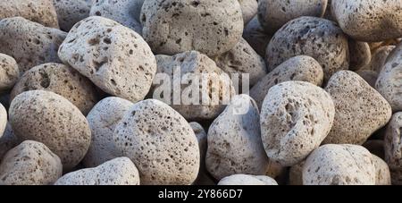 Helles Bimsgestein bildet einen strukturierten Hintergrund in Grau, weiß und Braun, der eine vulkanische Atmosphäre verleiht. Nahaufnahme hebt die feste, harte Natur von Steinen hervor Stockfoto