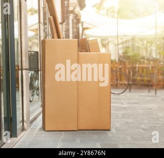 Zwei Pappschachteln voller Sachen stehen auf der Straße, von Tür zu Tür getrennte Abfallsammlung. Stockfoto