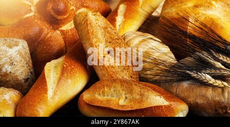 Frisch gebackene Brotlaibe mit Weizenohren bilden einen köstlichen Hintergrund. Goldbraune Krusten glitzern und bieten eine Vielzahl von Leckereien aus Bäckerei Stockfoto