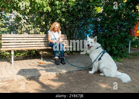 Seniorin eine Person allein mit Hund Görlitzer Park Görli Kreuzberg Berlin Deutschland Europa auf einer Bank sitzt Stockfoto