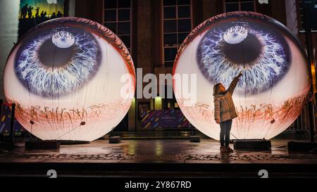 Essen, NRW, Deutschland. Oktober 2024. Besucher interagieren mit der Installation „Oculus“ der Künstler H:E:M (Italien) außerhalb des Grillo-Theaters. Zwei riesige Kugeln leuchten in Form von zwei Augen, die in den Himmel blicken. Eröffnungsabend des jährlichen Essen Light Festivals mit 16 großformatigen Lichtinstallationen in der ganzen Stadt. Das Festival ist frei zu sehen und findet jeden Abend von Sonnenuntergang bis 23 Uhr vom 2. Bis 13. Oktober 2024 statt. Quelle: Imageplotter/Alamy Live News Stockfoto