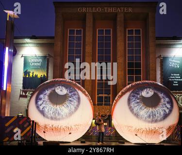 Essen, NRW, Deutschland. Oktober 2024. Besucher interagieren mit der Installation „Oculus“ der Künstler H:E:M (Italien) außerhalb des Grillo-Theaters. Zwei riesige Kugeln leuchten in Form von zwei Augen, die in den Himmel blicken. Eröffnungsabend des jährlichen Essen Light Festivals mit 16 großformatigen Lichtinstallationen in der ganzen Stadt. Das Festival ist frei zu sehen und findet jeden Abend von Sonnenuntergang bis 23 Uhr vom 2. Bis 13. Oktober 2024 statt. Quelle: Imageplotter/Alamy Live News Stockfoto