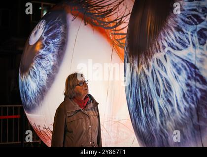 Essen, NRW, Deutschland. Oktober 2024. Besucher interagieren mit der Installation „Oculus“ der Künstler H:E:M (Italien) außerhalb des Grillo-Theaters. Zwei riesige Kugeln leuchten in Form von zwei Augen, die in den Himmel blicken. Eröffnungsabend des jährlichen Essen Light Festivals mit 16 großformatigen Lichtinstallationen in der ganzen Stadt. Das Festival ist frei zu sehen und findet jeden Abend von Sonnenuntergang bis 23 Uhr vom 2. Bis 13. Oktober 2024 statt. Quelle: Imageplotter/Alamy Live News Stockfoto