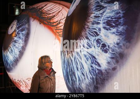 Essen, NRW, Deutschland. Oktober 2024. Besucher interagieren mit der Installation „Oculus“ der Künstler H:E:M (Italien) außerhalb des Grillo-Theaters. Zwei riesige Kugeln leuchten in Form von zwei Augen, die in den Himmel blicken. Eröffnungsabend des jährlichen Essen Light Festivals mit 16 großformatigen Lichtinstallationen in der ganzen Stadt. Das Festival ist frei zu sehen und findet jeden Abend von Sonnenuntergang bis 23 Uhr vom 2. Bis 13. Oktober 2024 statt. Quelle: Imageplotter/Alamy Live News Stockfoto