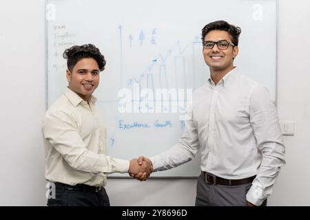 Lächelnde indische männliche Geschäftspartner begrüßen sich selbstbewusst mit einem Handschlag und lernen sich bei einer Bürositzung kennen. Fröhliche und vielfältige Multiple Stockfoto