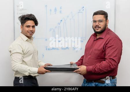Erfolgreiche Projektübergabe: Zwei Partner tauschen Vertragsordner aus und heben Partnerschaft und Kundenzufriedenheit nach Projektabschluss hervor Stockfoto