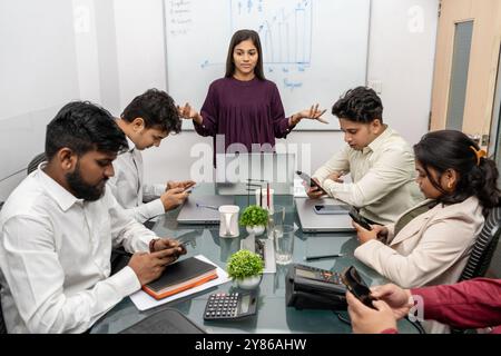 Frustrierte Führungskraft, die Unmut über das Meeting wegen unvollständiger Forschung zum Ausdruck bringt, verleumdete Mitarbeiter, die unter Druck stehen, sich mit ausstehenden Aufgaben zu befassen. Stockfoto