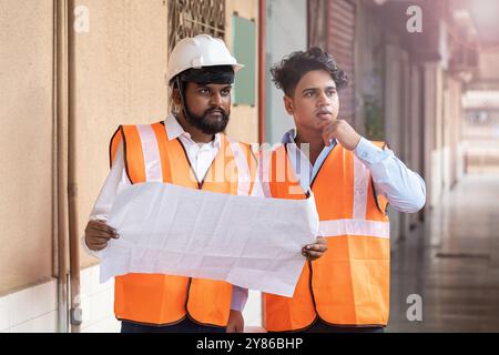 Ein Bauingenieur und ein Elektroingenieur konzentrieren sich auf die Prüfung von Baudetails, Projektaktualisierungen auf einer gewerblichen Industriebaustelle, Stockfoto
