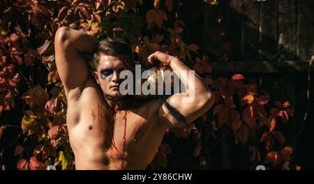 Tod - junger Mann Halloween-Porträt. Halloween oder Horror-Konzept - schreiender, toter Zombie. Junger Mann mit muskulösem Körper und Kürbis. Sport und Stockfoto