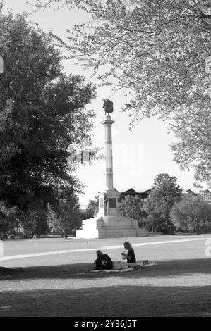 Junges kaukasisches Paar, das sich am Calhoun Monument am Marion Square in Charleston, South Carolina, USA, entspannt. Die Statue wurde zu Ehren von John C. Calhoun gebaut. Stockfoto