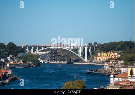 Porto, Portugal - 13. September 2024 : Ein klarer blauer Himmel überblickt den Fluss mit einer modernen Brücke, die beide Flüsse verbindet. Stockfoto