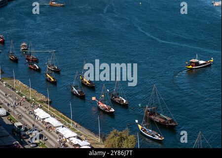 Porto, Portugal - 13. September 2024 : lebhafter Blick auf den Fluss mit traditionellen Booten, die entlang des Ufers in einer belebten Stadt angedockt werden Stockfoto
