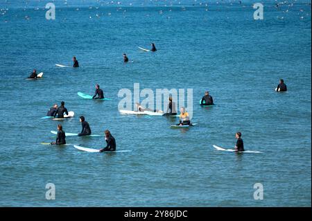 Porto, Portugal - 13. September 2024 : mehrere Surfer paddeln und warten auf Wellen im Meer unter hellem Sonnenlicht. Stockfoto