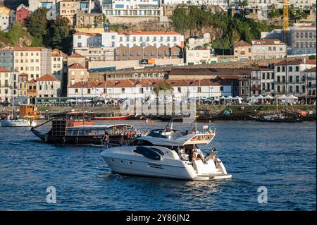 Porto, Portugal - 13. September 2024 : zwei Boote gleiten durch den Fluss Douro mit der Stadt Porto im Hintergrund. Stockfoto