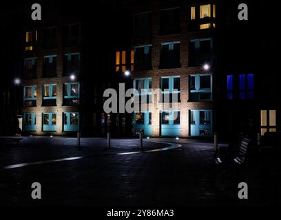 Parkbänke vor beleuchteten Apartments an den historischen Docks von Gloucester bei Nacht im Winter Stockfoto