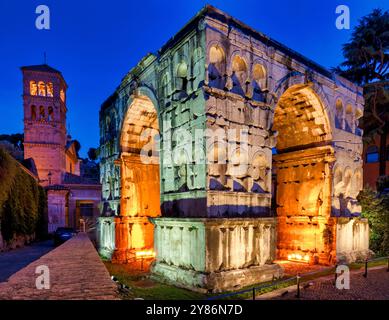 Arco di Giano und der Glockenturm von San Giorgio in Velabro in Rom, Italien, beleuchtet in der Dämmerung. Stockfoto